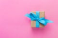 Gift wrapped and decorated with blue bow on pink background with copy space. Flat lay, top view Royalty Free Stock Photo