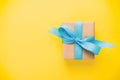 Gift wrapped and decorated with blue bow on yellow background with copy space vintage, toned. Flat lay, top view Royalty Free Stock Photo