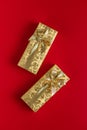 Gift wrapped in gold foil. Christmas present with gold ribbon on red background. Top view Royalty Free Stock Photo