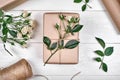Gift wrapping background, copy space. Rolls of kraft wrapping paper, twine, branch of roses, gift box on wooden background