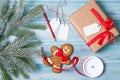 Gift wrapping, gift box with tags, ribbon, gingerbread man and snow fir tree branch, wooden background, top view Royalty Free Stock Photo