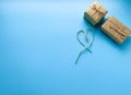 Gift wrapping in kraft paper with a heart made of threads on a blue background. Minimalism. The concept of the holiday, love, birt