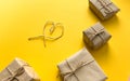 Gift wrapping in kraft paper with a heart made of threads on a yellow background. Minimalism. The concept of the holiday, love, bi