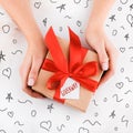 Gift wrapping. Packaging modern christmas present boxes in stylish gray paper with satin red ribbon. Top view of hands Royalty Free Stock Photo