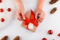 Gift wrapping. Packaging modern christmas present boxes in stylish gray paper with satin red ribbon. Top view of hands Royalty Free Stock Photo