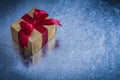 Giftbox wrapped in shining golden paper on metallic surface