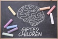 Gifted Children and education concept written on a blackboard in a classroom. Brain drawing and some colored chalk on a chalkboard