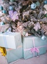 Gifts in boxes with bows under a delicate Christmas tree