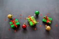 Gifts in green paper with red and yellow ribbons, gold, red and green christmas balls lie in a row. Confetti in the form of red Royalty Free Stock Photo