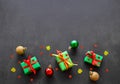 Gifts in green paper with red and yellow ribbons, gold, red and green christmas balls lie in a row. Confetti in the form of red Royalty Free Stock Photo