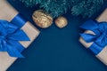 Gifts in paper with blue ribbon and bow-knots with gold nuts and branches of spruce on a dark-blue background