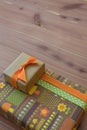 Gifts in retro paper with flowers and mushrooms, orange brown and green, diagonal on neutral wood table