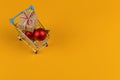 Gifts in a small shopping trolley on a yellow background, concept, copy space Royalty Free Stock Photo