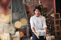 Gifts time. Young man standing in the beautiful decorated room and holding white box with present in the New year time