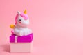 Gifts, unicorn figurine and gift box for a party on a pink background