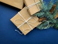 Gifts wrapped in craft paper and tied with a scourge next to fir branch