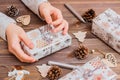 Gifts wrapped in festive paper in children`s hands and Christmas decorations on a wooden background.  Christmas preparations Royalty Free Stock Photo