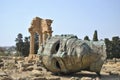 Gigantic Greek sculpture head in front of ancient Greek Temple a Royalty Free Stock Photo