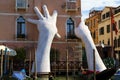 Gigantic hands rise from water to support building - sculpture b