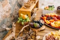 Gilded bowls with blue and white grapes, figs and pears on a wooden table with ham, cheese and fruits on a tray. Royalty Free Stock Photo