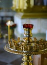 Gilded candlestick with one burning candle and a small Christian cross