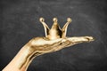 Gilded female hand holding a golden crown with dark chalkboard background. Royalty, succes and high quality concept Royalty Free Stock Photo