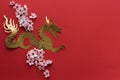 Gilded paper dragon with plum blossoms on red card. Copy space. Chinese New Year Royalty Free Stock Photo