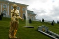 Gilded statue of Capitoline Antinous against grassy slope with fountain and Big Peterhof Palace in Saint-Petersburg, Russia Royalty Free Stock Photo