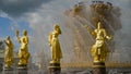 Gilded statues on background of fountain. Action. Beautiful Golden statues of women Shine on background of splashing