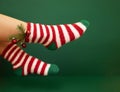 Gils feet in fluffy New Year warm socks. Christmas tree branch with balls decorats female leg Royalty Free Stock Photo