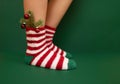 Gils feet in fluffy New Year warm socks. Christmas tree branch with balls decorats female leg. Studio shot Royalty Free Stock Photo