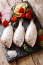 Gilt-head sea bram fish with ingredients close-up on a slate board. vertical Royalty Free Stock Photo