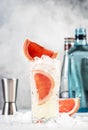 Gin bitter lemon trendy alcoholic cocktail drink with dry gin, tonic, grapefruit and ice cubes, bar tools. Gray background with Royalty Free Stock Photo