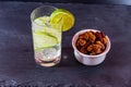 Gin and tonic with bowl of mixed roast nuts.