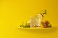Gin tonic cocktail with lemon and rosemary on a yellow background