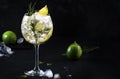 Gin tonic lime alcoholic cocktail drink with dry gin, rosemary, tonic and ice in big wine glass. Black bar counter background, Royalty Free Stock Photo