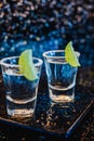 Gin or vodka with lime. Two glasses with a cocktail alcohol with lemons on the black blue surface.