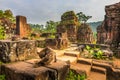 Ginger and black striped cat perched atop an ancient stone wall at My Son Ruins Cham Temple Site Royalty Free Stock Photo