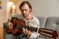 Ginger bristle man playing guitar while sitting on couch Royalty Free Stock Photo