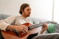 Ginger bristle man playing guitar while sitting on couch Royalty Free Stock Photo