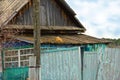 A ginger cat lies on the roof of an old rustic wooden house. The cat looks at the clouds in the sky. Royalty Free Stock Photo