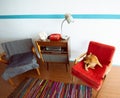 Ginger cat resting on old fashioned armchair in cosy vintage room with retro radio turntable, telephone and standart lamp. Royalty Free Stock Photo