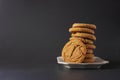 A ginger cookie leans on a stack of cookies on a white plate with a black background Royalty Free Stock Photo