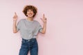 Ginger curly woman posing with fingers crossed for best luck