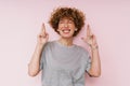 Ginger curly woman posing with fingers crossed for best luck