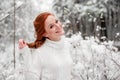 Ginger cute female in white sweater in winter forest. Snow december in park. Portrait. Christmas cute time. Royalty Free Stock Photo