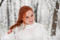 Ginger european girl in white sweater in winter forest. Snow december in park. Christmas cute time.