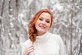 Ginger european girl in white sweater in winter forest. Snow december in park. Christmas wonderful time. Royalty Free Stock Photo