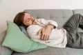 Ginger european man feeling sick while lying on couch