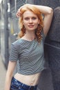 Ginger girl against wall of building, photo toned